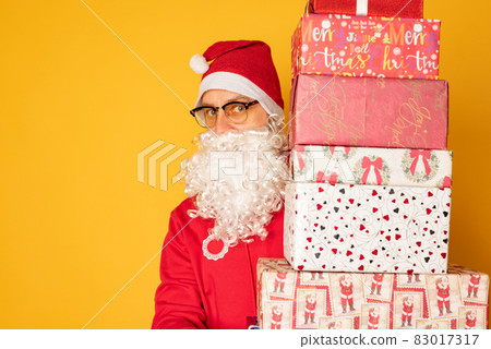 Santa Claus brought gifts for Christmas. Modern young santa on yellow background Santa Claus brought gifts for Christmas. Modern young santa on yellow background 83017317
