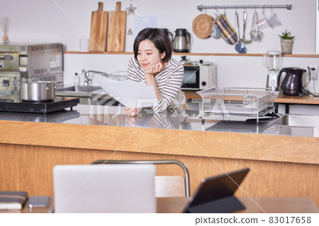 A young woman standing up and looking at materials by teleworking 83017658