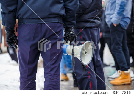 police officer holding loudspeaker megaphone outdoors, close-up 83017816