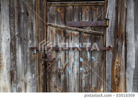 old wooden barn door with iron padlocks and rustes steel reinforcement bands old wooden barn door with iron padlocks and rustes steel reinforcement bands 83018309