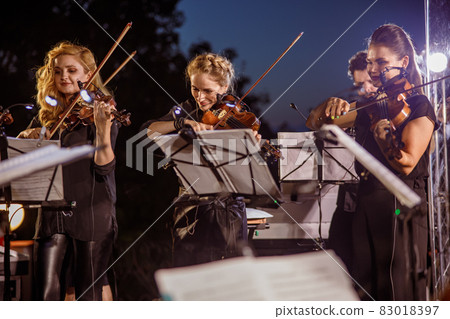 Female violin players playing in orchestra at night Female violin players playing in orchestra at night 83018397