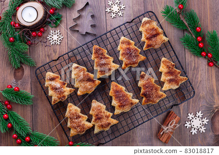 Christmas tree shaped puff pastry cookies with sugar and cinnamon on a cooling rack Christmas tree shaped puff pastry cookies with sugar and cinnamon on a cooling rack 83018817