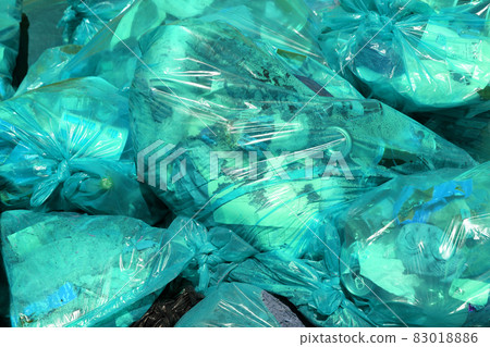 full frame background of turquoise plastic trash bags with generic domestic waste 83018886