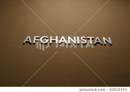the word afghanistan laid with silver metal letters on rough tan khaki canvas fabric 83019354
