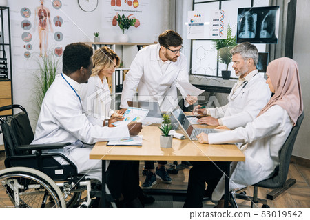 Multicultural group of doctors working on gadgets at office Multicultural group of doctors working on gadgets at office 83019542