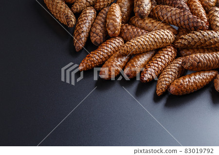 pile of fir cones on black plastic background 83019792