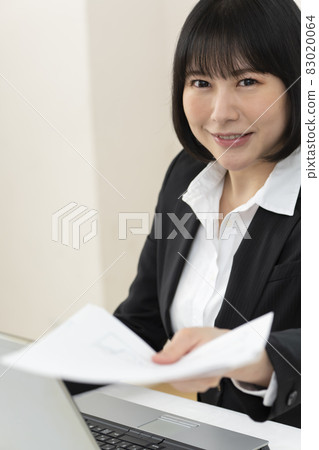 坐在辦公桌前遞文件的年輕女子 83020064