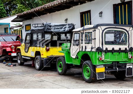 Traditional off-road vehicles parked at a beautiful street in the small town of Salento located at the region of Quindio in Colombia 83022127