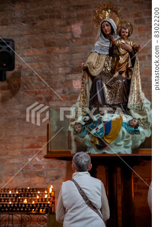 Senior woman praying at the historical Cathedral of Our Lady of Poverty of Pereira, built in 1890 83022200