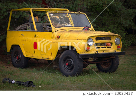 Old open UAZ soviet union yellow van standing on grass near woods Old open UAZ soviet union yellow van standing on grass near woods 83023437