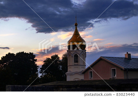 Orthodox church with golden dome on dark blue sunset sky with heavy clouds Orthodox church with golden dome on dark blue sunset sky with heavy clouds 83023440