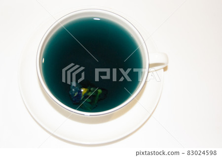The mood color is blue - blue tea in a white mug, which stands on a white saucer and a white tray. The mood color is blue - blue tea in a white mug, which stands on a white saucer and a white tray. 83024598