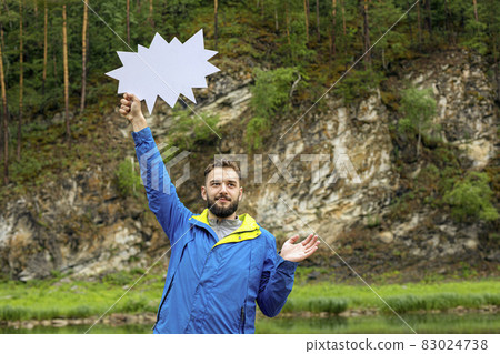 young bearded man with blank speech bubble on background of natural landscape. pay attention, way up, look up young bearded man with blank speech bubble on background of natural landscape. pay attention, way up, look up 83024738