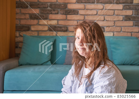 Sad young woman sitting at home. Looking at camera. Frustrated emotions Sad young woman sitting at home. Looking at camera. Frustrated emotions 83025566