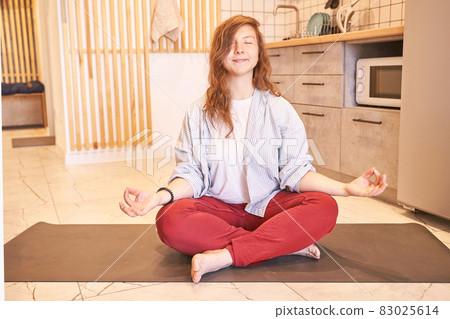 Young woman going yoga exercise at kitchen. Health care online lessons. Fitness 83025614