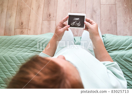 Pregnant belly with ultrasound result picture. Woman see unborned kid face Pregnant belly with ultrasound result picture. Woman see unborned kid face 83025713