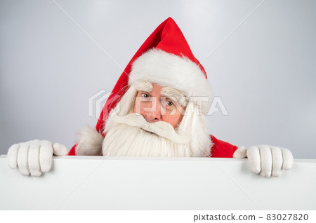 Santa Claus peeks out from behind an ad on a white background. Merry Christmas. 83027820