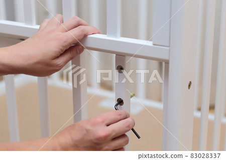 Daddy's hand assembling a crib Daddy's hand assembling a crib 83028337