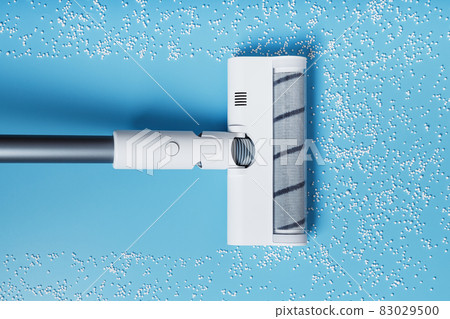 The turbo brush of the vacuum cleaner cleans white balls, top view on a blue background. The concept of cleanliness and cleaning. 83029500
