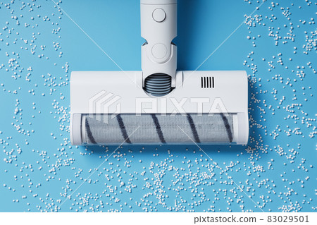 The turbo brush of the vacuum cleaner cleans white balls, top view on a blue background. The concept of cleanliness and cleaning. The turbo brush of the vacuum cleaner cleans white balls, top view on a blue background. The concept of cleanliness and cleaning. 83029501