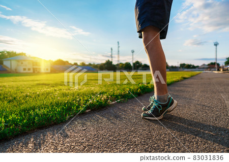 teen boy boy does physical exercises at the stadium track, close view of the legs, a soccer field with green grass - concept of sports and health teen boy boy does physical exercises at the stadium track, close view of the legs, a soccer field with green grass - concept of sports and health 83031836