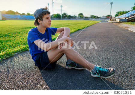 concept of sports and health - portrait of a teen boy posing at a stadium track, a soccer field with green grass concept of sports and health - portrait of a teen boy posing at a stadium track, a soccer field with green grass 83031851