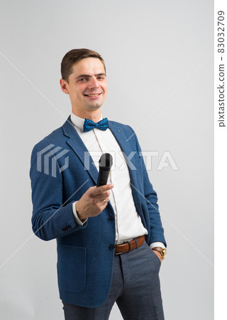 The entertainer. Young elegant talking man holding microphone, Isolated in studio. 83032709