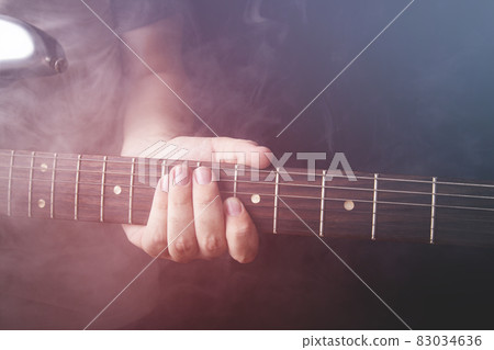 Hands of man playing electric guitar wiht smoke. Focus on hand.. Hands of man playing electric guitar wiht smoke. Focus on hand.. 83034636
