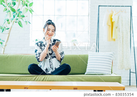 年輕女子在客廳看智慧型手機 年輕女子在客廳看智慧型手機 83035354