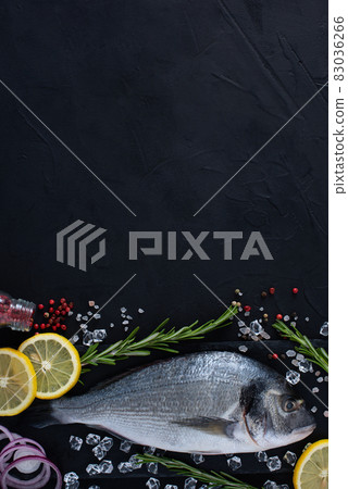 Raw dorada fish on dark background with rosemary, lemon and pepper. Raw dorada fish on dark background with rosemary, lemon and pepper. 83036266