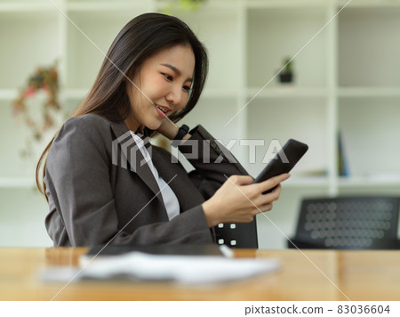 Female employee relaxed on her smartphone, scrolling through social media 83036604