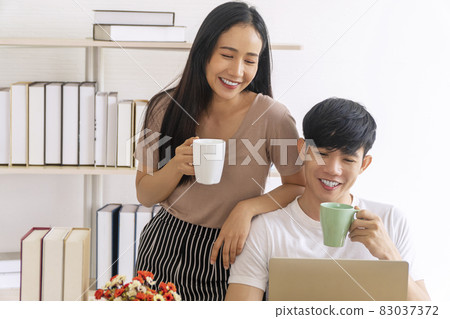 Lifestyle quarantine technology family concept. Happiness young couple freelancer holding cup 83037372