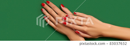 Womans hands with trendy christmas red manicure on green background 83037632