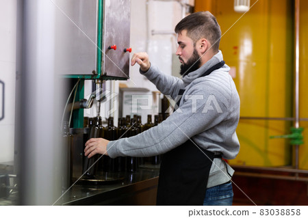 Young man working on olive oil bottling line Young man working on olive oil bottling line 83038858