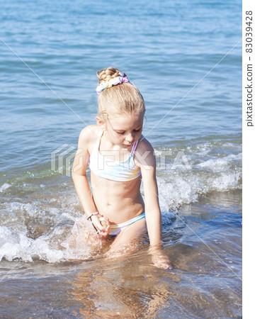 Little girl playing on the beach by the sea 83039428