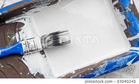 Close up of a paintbrush for a house in a paint tray. 83040248