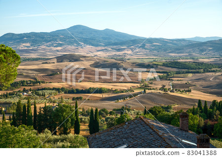 Tuscany, Italy. August 2020. Amazing landscape of the Tuscan countryside with the typical rolling hills and cypresses to mark the boundaries. Tuscany, Italy. August 2020. Amazing landscape of the Tuscan countryside with the typical rolling hills and cypresses to mark the boundaries. 83041388