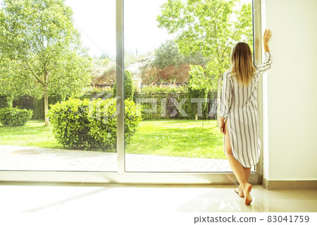 Hotel room full of sunlight sun beams. Optimistic start. Blond woman, cozy home clothing, morning daylight. New day new me concept Hotel room full of sunlight sun beams. Optimistic start. Blond woman, cozy home clothing, morning daylight. New day new me concept 83041759