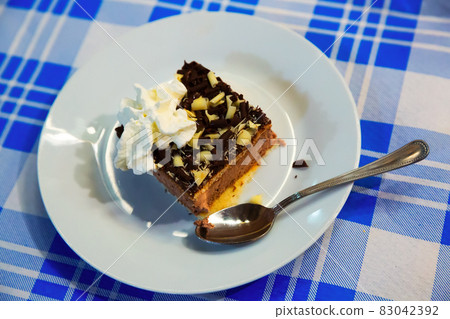 Slice of soft biscuit cake with cream and chocolate 83042392