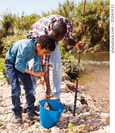 Man and boy with bucket of catch 83042412