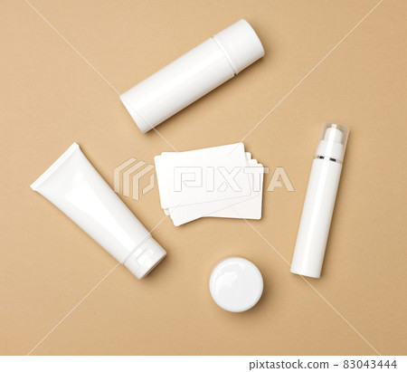 jar, bottle and empty white plastic tubes for cosmetics on a beige background. Packaging for cream, gel, serum, advertising and product promotion, mock up, top view 83043444