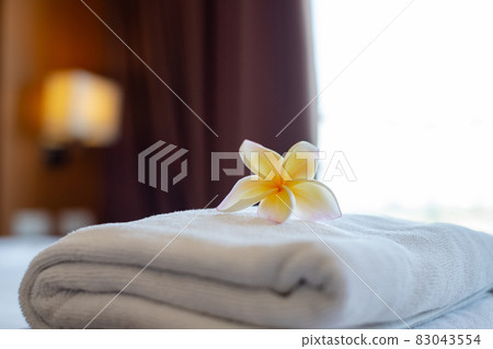 A hotel maid stacked towels on the bed and placed flowers on the towels in a hotel room A hotel maid stacked towels on the bed and placed flowers on the towels in a hotel room 83043554