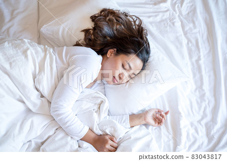 A young Asian woman sleeps comfortably in a hotel room with a happy face. It is a good rest during the long holidays. Top view 83043817