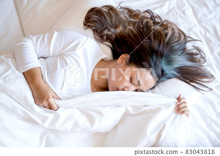 A young Asian woman sleeps comfortably in a hotel room with a happy face. It is a good rest during the long holidays. Top view 83043818