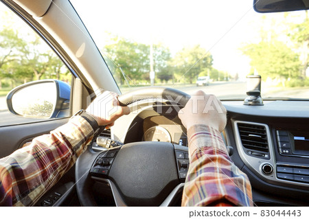 Car interior with male driver sitting behind the wheel, soft sunset light. Luxurious vehicle dashboard and electronics. Car interior with male driver sitting behind the wheel, soft sunset light. Luxurious vehicle dashboard and electronics. 83044443