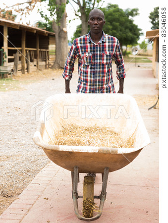 Young man farmer with barrow during working at farm 83046058