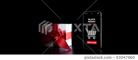 Online shopping gifts. Black Friday banner with internet shopping app on mobile phone, white gifts with red bow falling on black background. Present online concept. 83047860