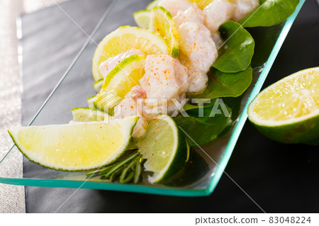 Seafood ceviche from hake on a glass plate with lime and greens Seafood ceviche from hake on a glass plate with lime and greens 83048224