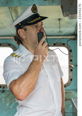Navigation officer manage ship with transmitter. Captain standing in the wheelhouse. Navigation officer manage ship with transmitter. Captain standing in the wheelhouse. 83049276