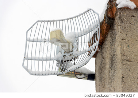 The directional outdoor antenna with fallen and frozen snow is mount to the chimney 83049327